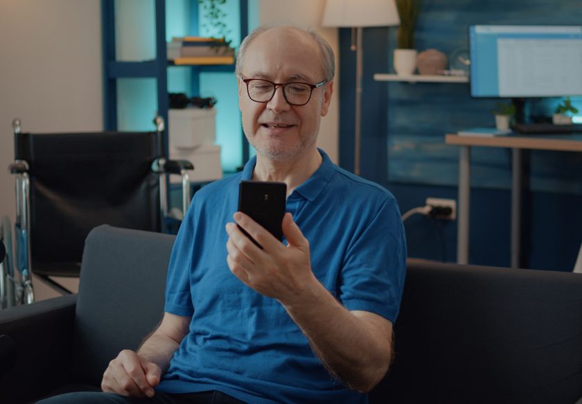 Retired man holding smartphone to chat on video call with family, using online teleconference for remote communication. Pensioner having conversation with people on videoconference meeting.