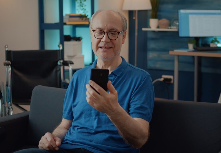 Retired man holding smartphone to chat on video call with family Retired man holding smartphone to chat on video call with family, using online teleconference for remote communication. Pensioner having conversation with people on videoconference meeting.