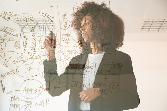 Focused young businesswomen writing on virtual board. Concentrated young African American female manager holding marker and making noted on chart. Strategy, business and management concept