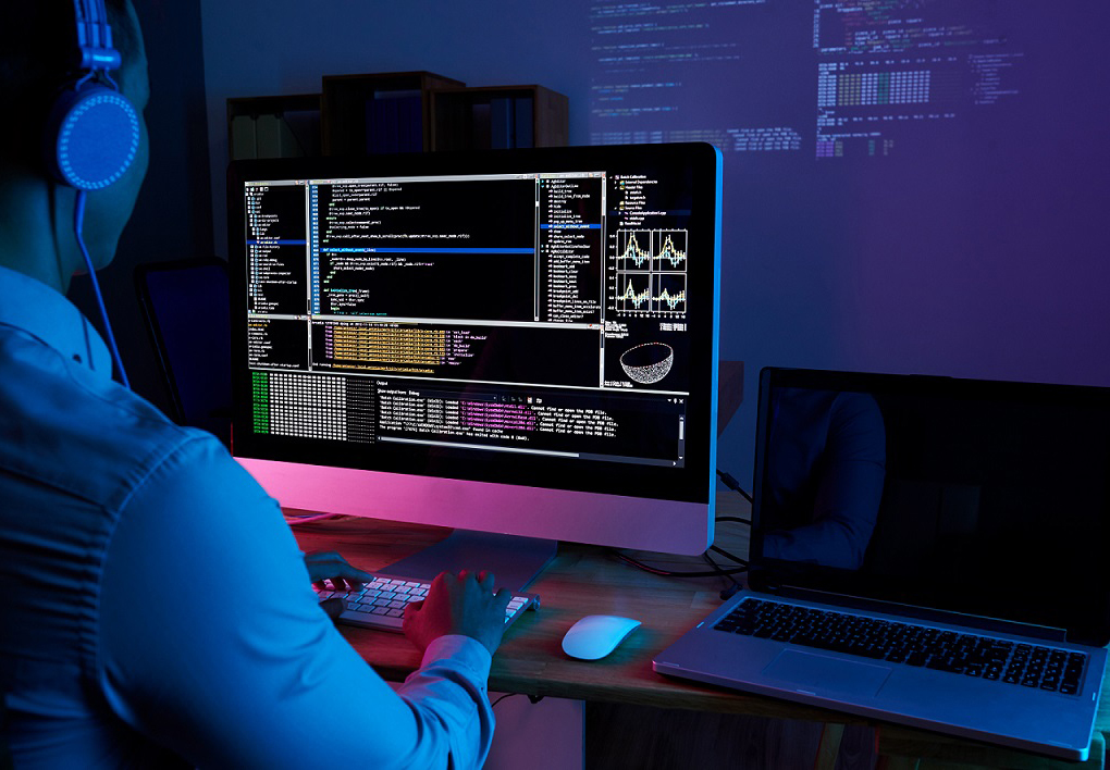 Programmer in headphones checking his code on computer screen