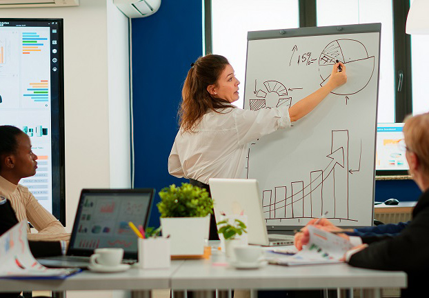 Focused team leader presenting marketing plan to interested multiracial coworkers. Serious speaker boss executive, business trainer explaining development strategy to motivated mixed race employees.